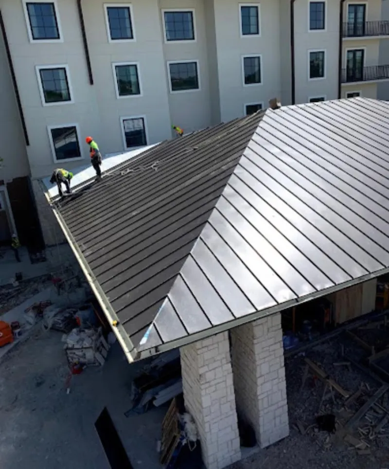 Crew installing standing seam metal roof panels on a commercial project in Abingdon